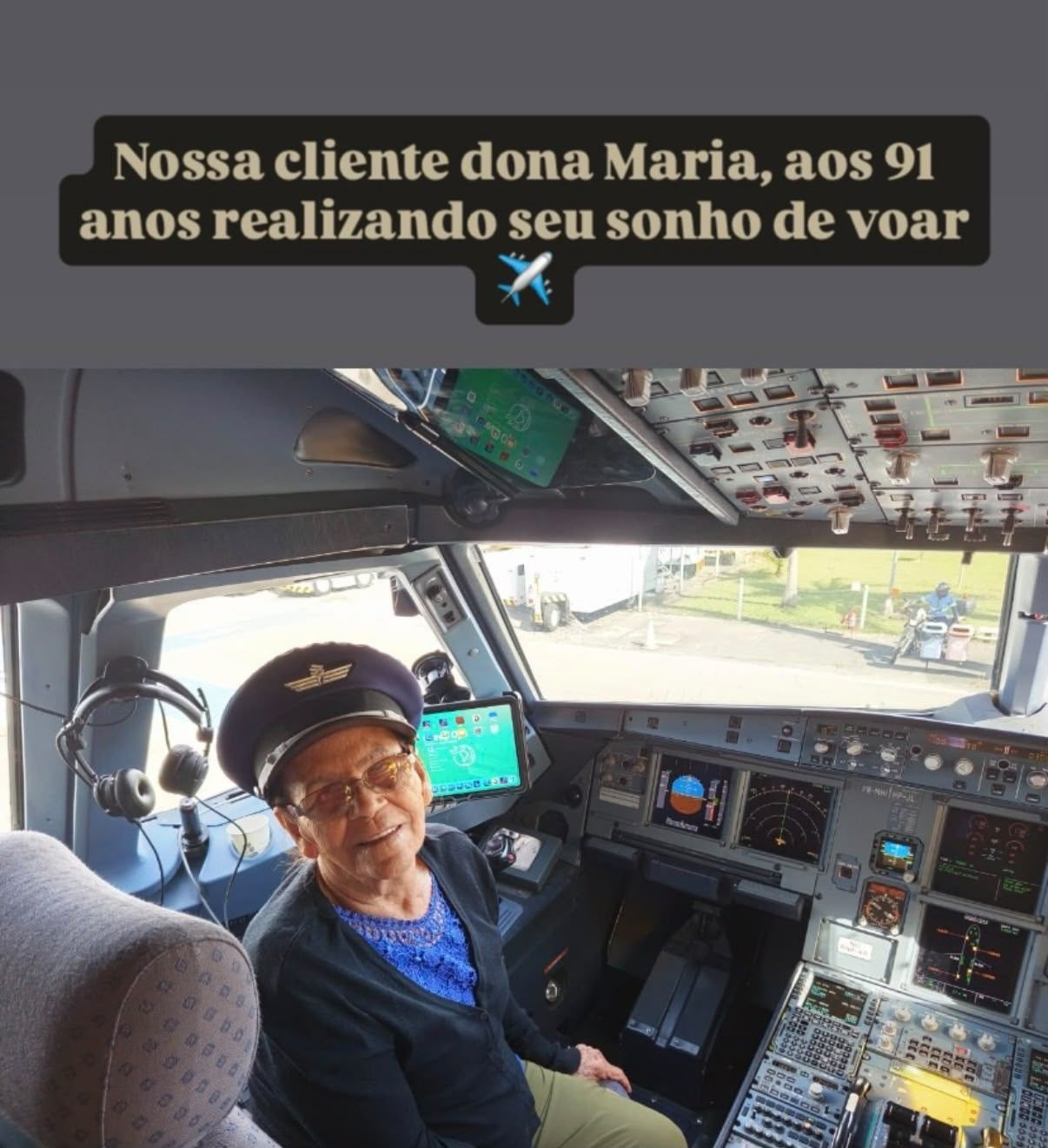 Dona Maria, cliente da Amaré Travel, sentada na cabine de comando de um avião