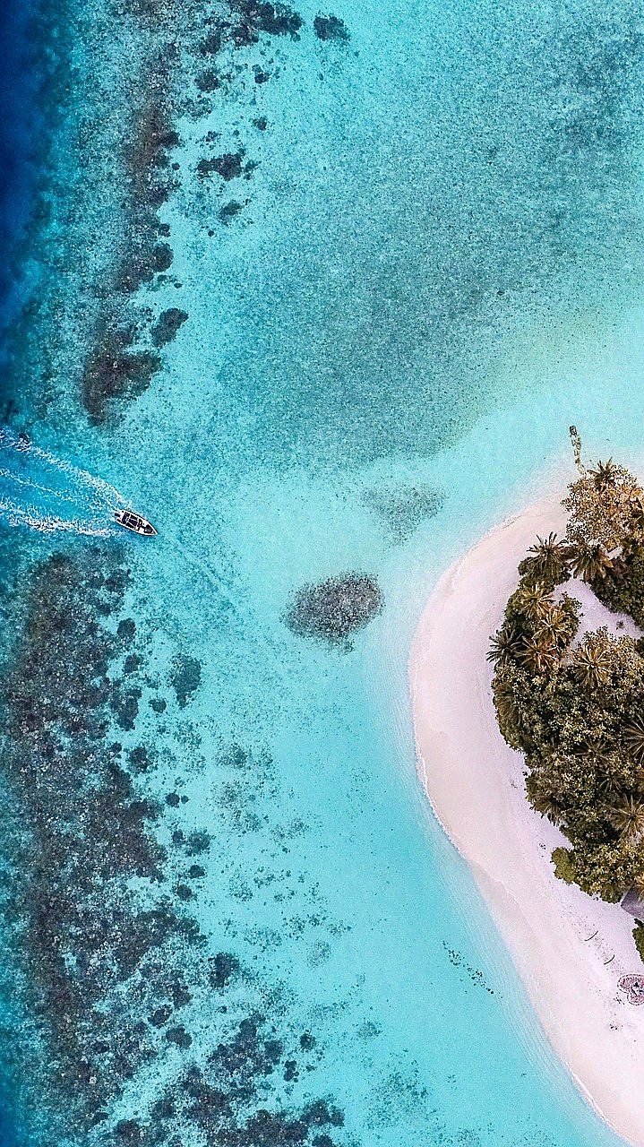 Mar turquesa visto de cima, com barco e faixa de areia
